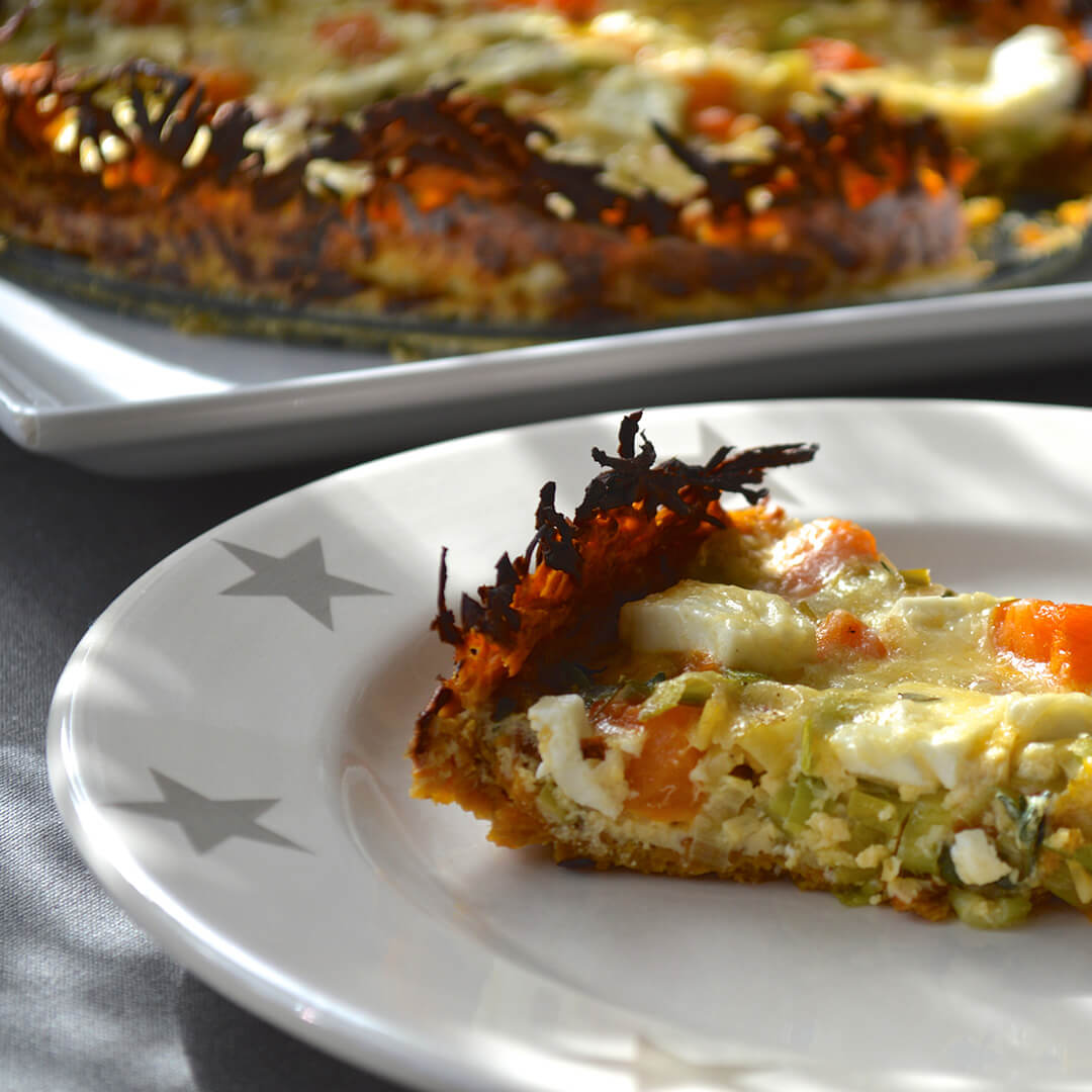 A plate of Sweet Potato Crust Tart next to a casserole dish of Sweet Potato Crust Tart