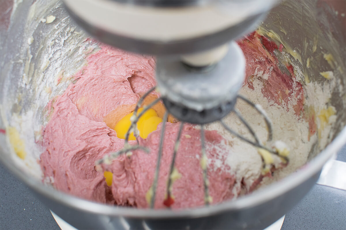 Cake batter being whisked with an electric whisk in metal bowl 