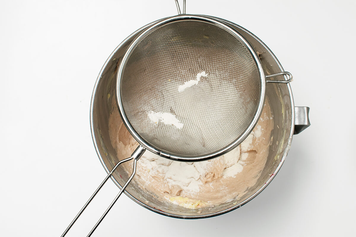 Flour being sieved into cake batter