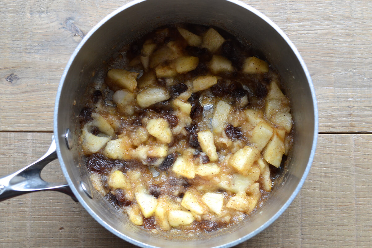 A saucepan of cooked apple, honey, cinnamon and raisins