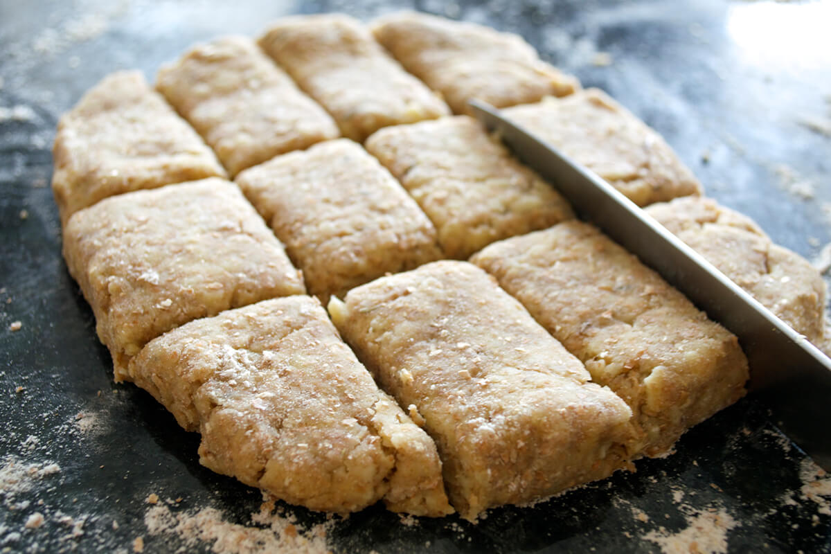 A floured surface with a rectangle of dough being cut into squares