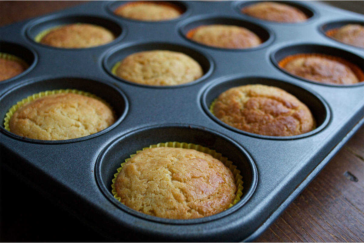 A cupcake tin with cooked cupcakes in paper cake cases