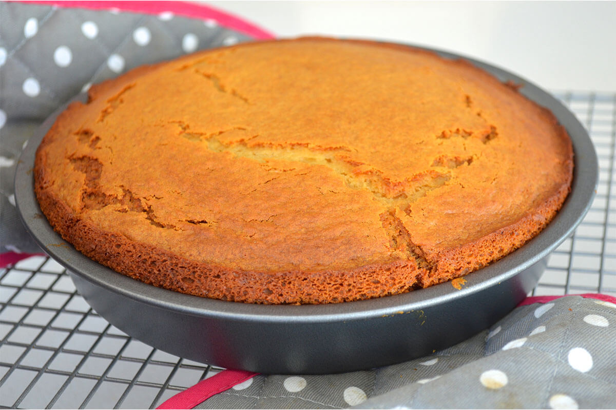 A cake in a cake tin on top of a cooling rack