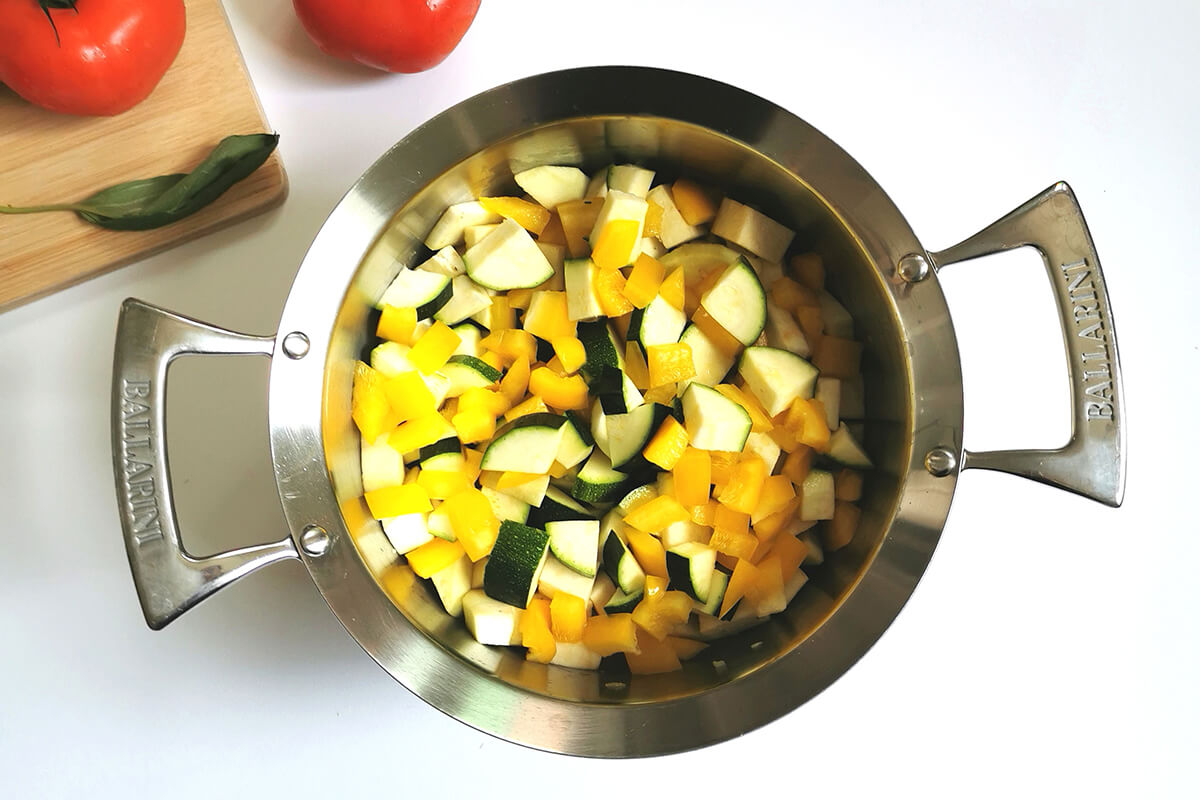 A saucepan of sauteed onions and garlic with cubed aubergine and courgette