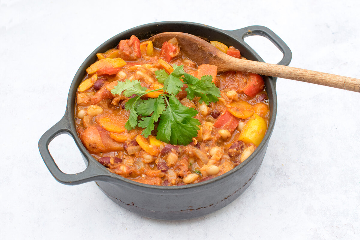 A saucepan of chunky vegetarian chilli topped with coriander