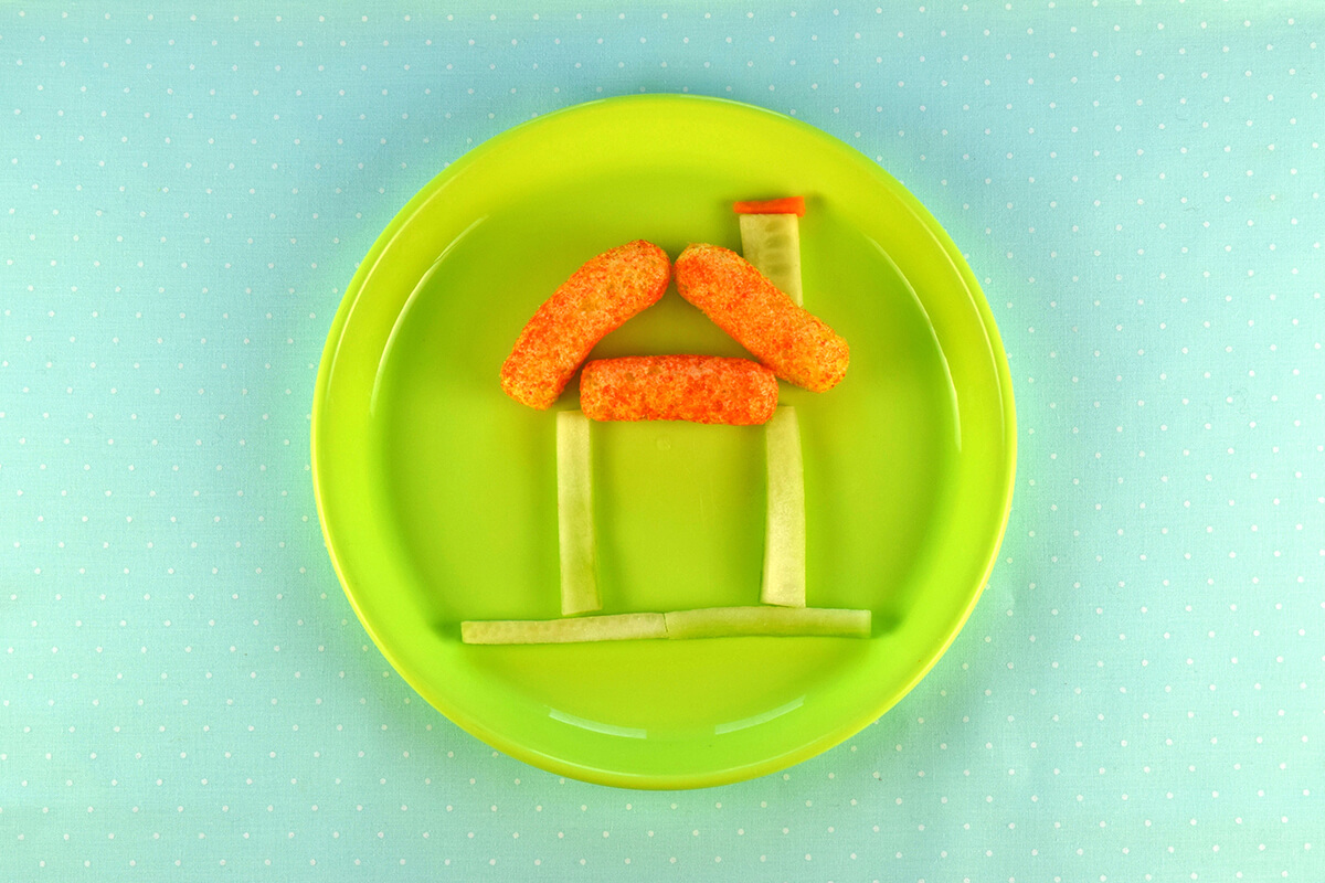 Cucumber rectangle placed on right side of roof with a sliver of carrot above it to create a chimney