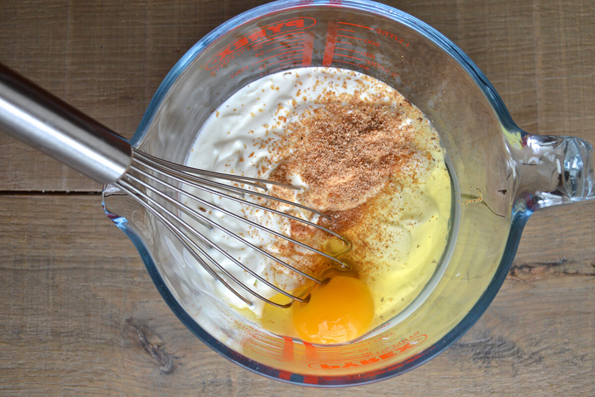 A measuring jug with Greek yoghurt, egg and grated nutmeg