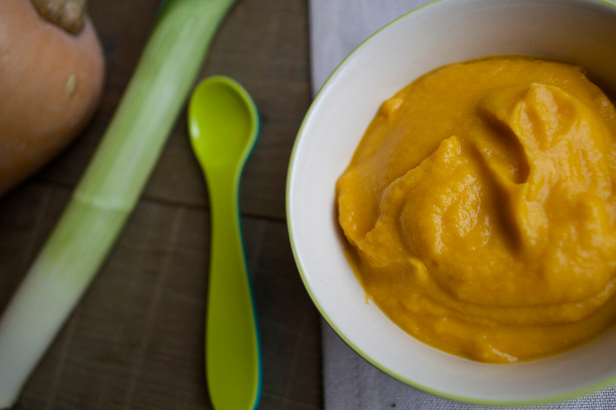 Leek, Butternut Squash & Cheese Puree in a bowl with a butternut squash and leek next to it