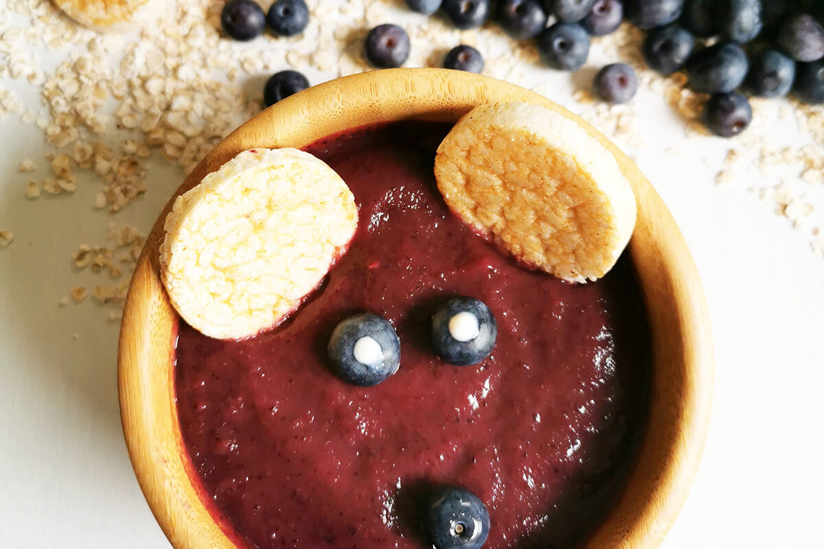 3 blueberry halves are placed in the bowl. 2 of them with a dot of plain yoghurt to create eyes and the third one placed to create a nose