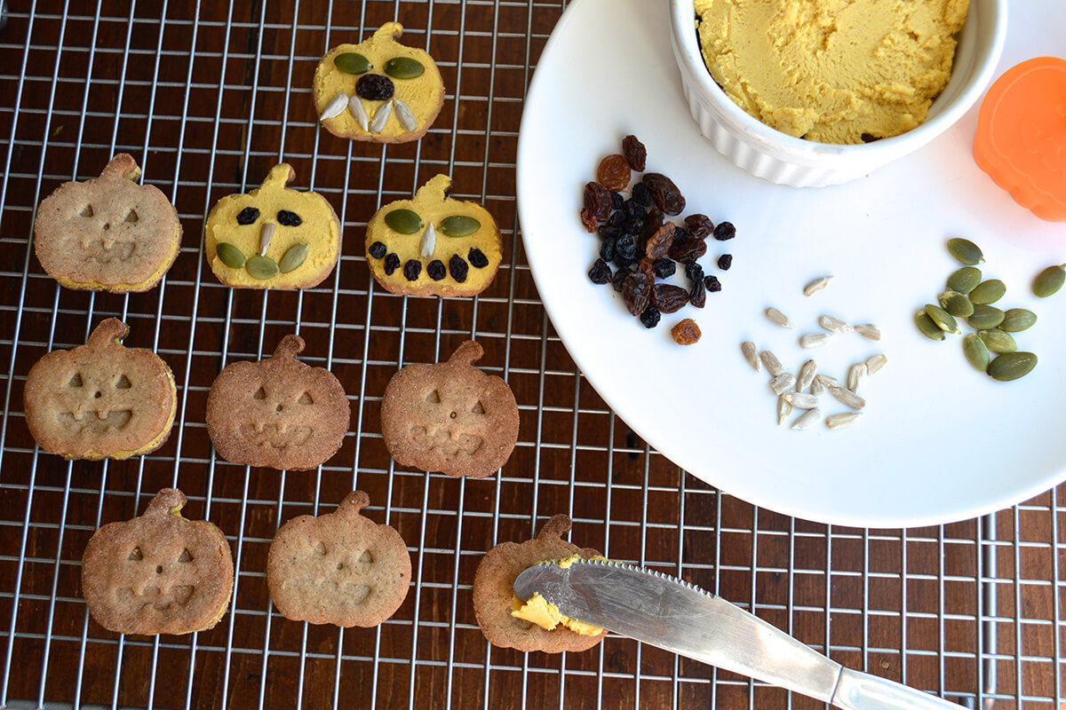 Pumpkin shaped biscuits being decorated to look like pumpkins