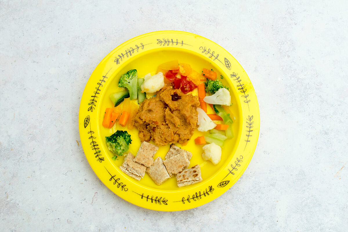 Red lentil dip served with flatbread, chopped broccoli and cauliflower florets and diced cherry tomatoes