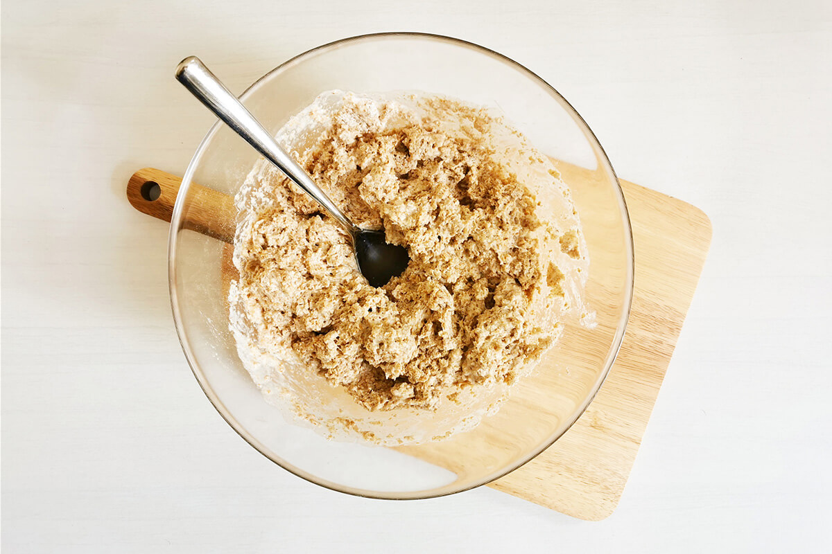 A glass bowl of soda bread dough on a wooden chopping board