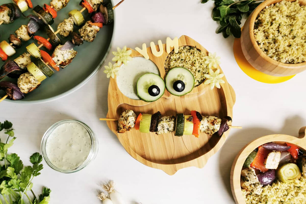 Tasty Chicken Kebabs & Couscous next to a plate of kebabs, a bowl of couscous, a smaller serving of kebabs and couscous and a small dish of yoghurt dip